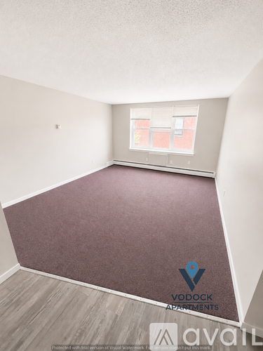A room with a carpeted floor and a window with a view of a building.