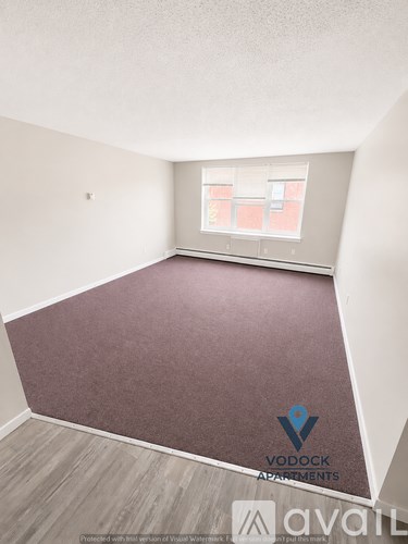 A room with a carpeted floor and a window with a view of a building.
