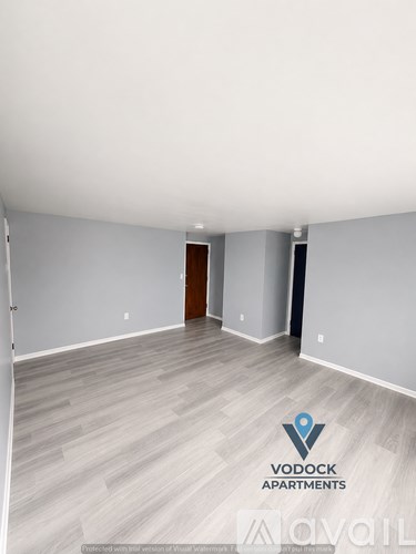 A spacious room with a wooden floor and a door in the distance.
