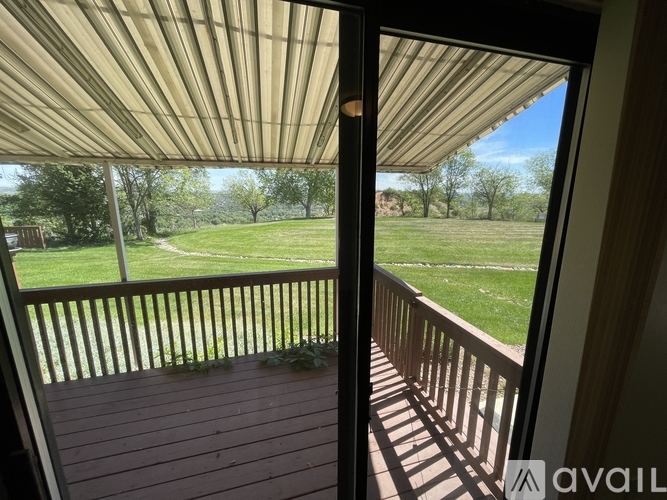 A balcony with a view of a green lawn and trees.