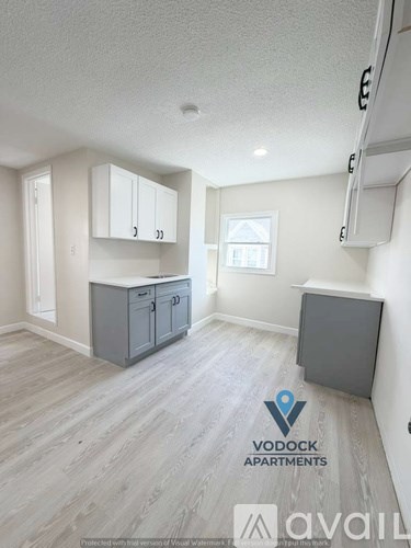 A spacious empty room with wooden flooring and a cabinet.