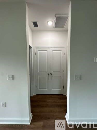A hallway with a white door and wooden floors.