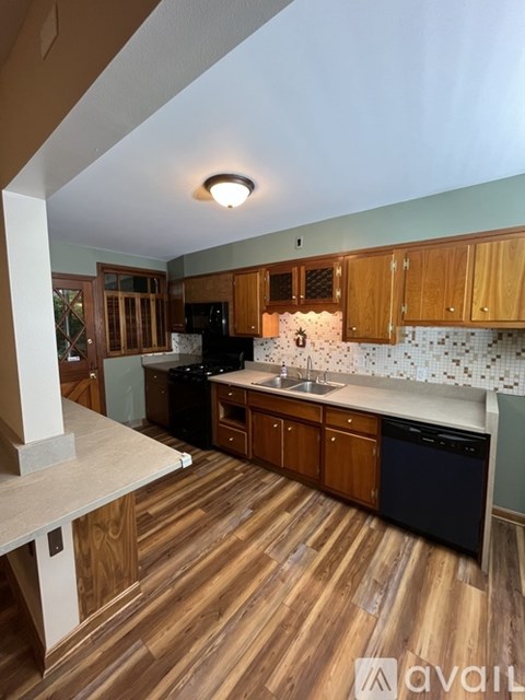 A kitchen with wooden cabinets and a black dishwasher.