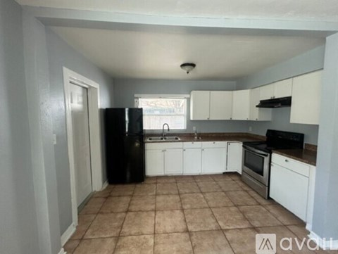 A kitchen with white cabinets and a black fridge.