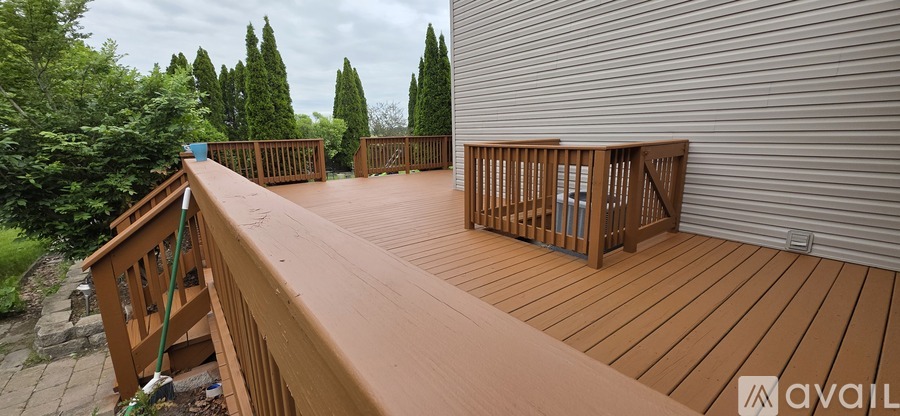 A wooden deck with a railing and trees in the background.