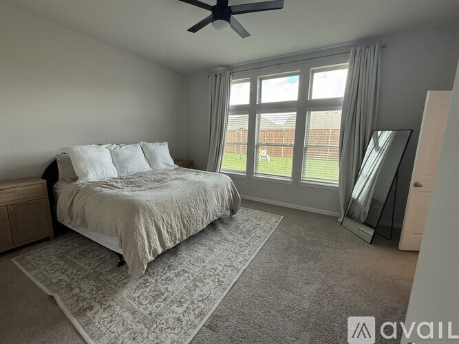A bedroom with a large bed and a ceiling fan.