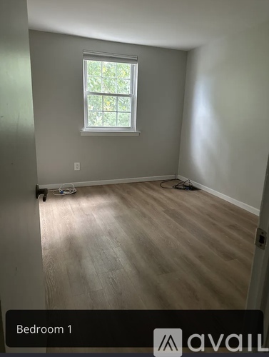 A room with a window and wooden flooring, labeled Bedroom 1.