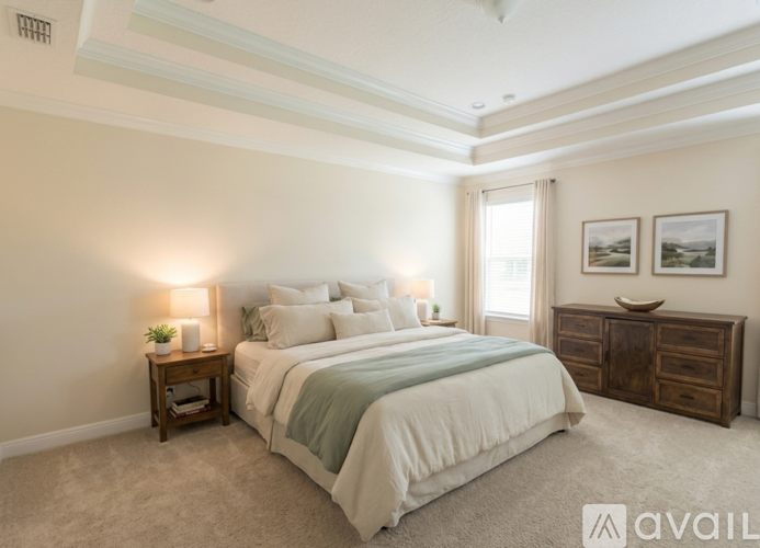 A bedroom with a large bed, a nightstand with a lamp, and a dresser with two drawers.