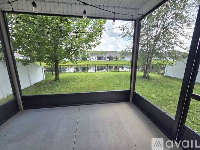 A patio with a view of a grassy area and trees.