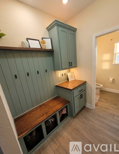 A kitchen with green cabinets and a wooden countertop.