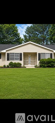 A house with a white door and windows is surrounded by greenery.