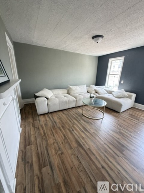 A living room with a white couch and a glass coffee table.