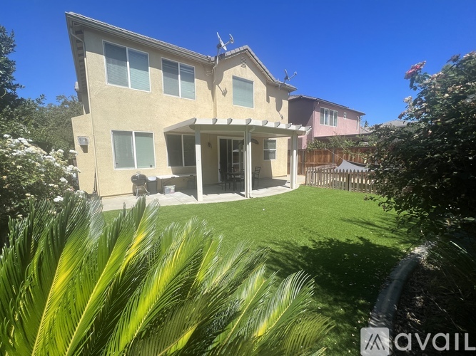 A house with a beige exterior and a green lawn in front.