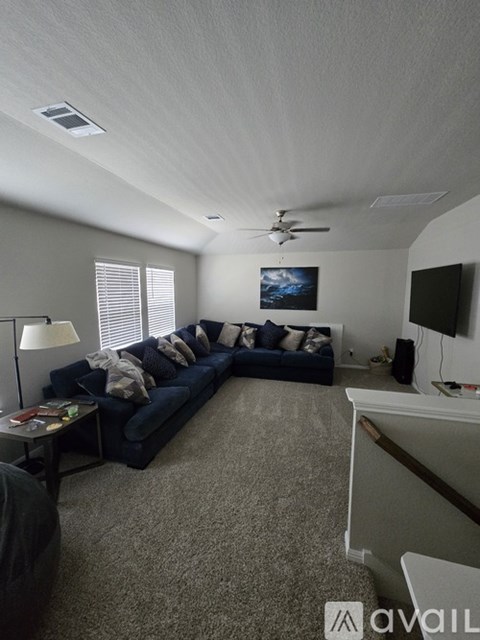 A living room with a blue couch and a ceiling fan.