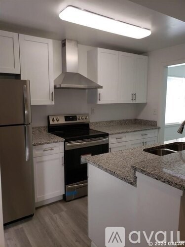 A kitchen with white cabinets and a granite countertop.
