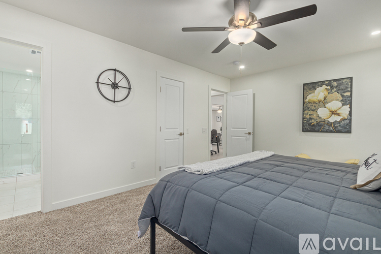 A bedroom with a bed, a ceiling fan, and a clock on the wall.