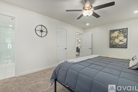 A bedroom with a bed, a ceiling fan, and a clock on the wall.