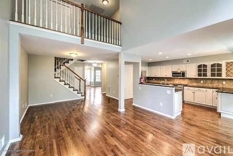 A spacious open floor plan with wood flooring and a staircase with a metal railing.