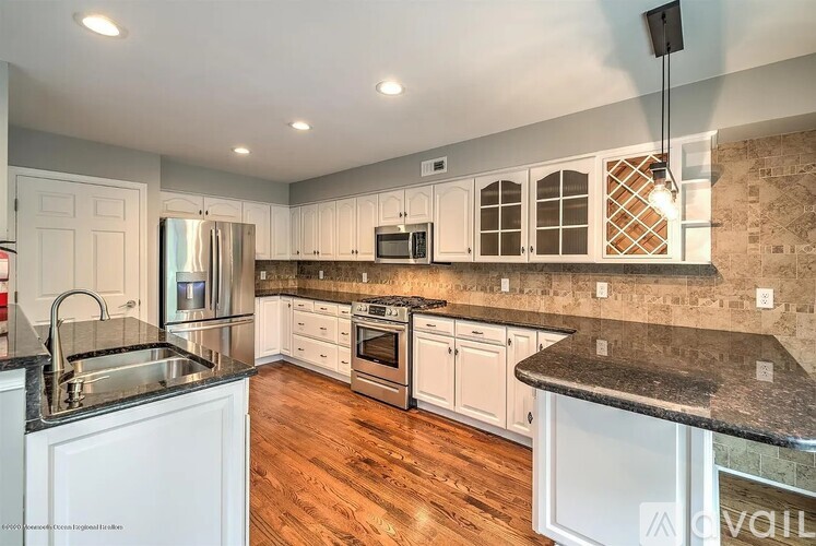 A kitchen with white cabinets and a black countertop.
