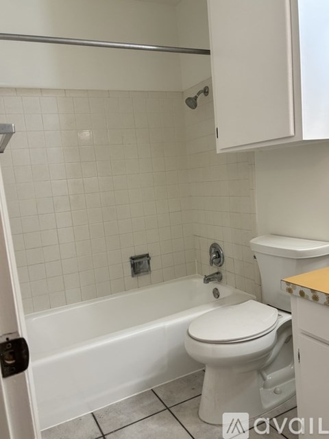 A white toilet in a bathroom with a white tiled wall.