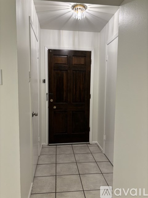 A hallway with a brown door and white walls.
