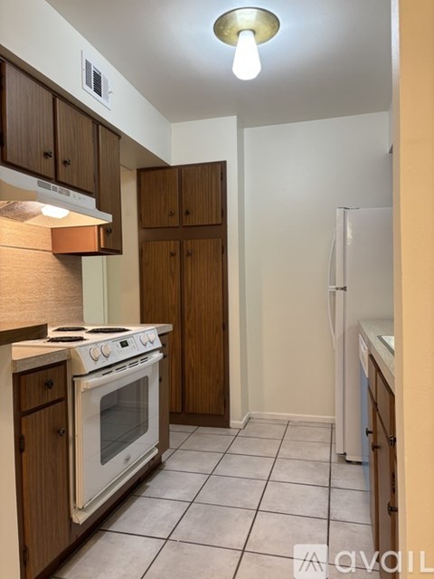 A kitchen with a stove, refrigerator, and cabinets.