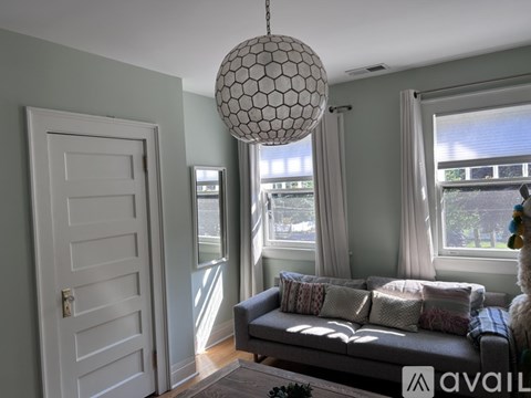 A living room with a grey couch and a hanging light fixture.