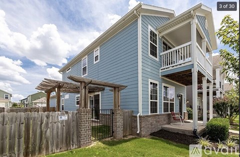 A blue house with a white fence and a balcony.