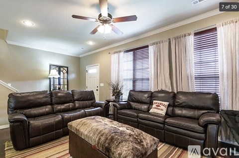 A living room with a brown leather couch and ottoman.