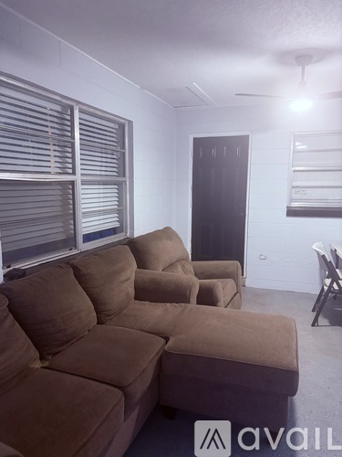 A living room with a brown couch and a fan.