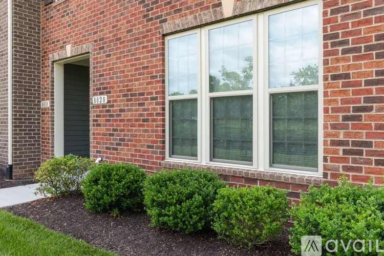 A brick house with a window and bushes in front.