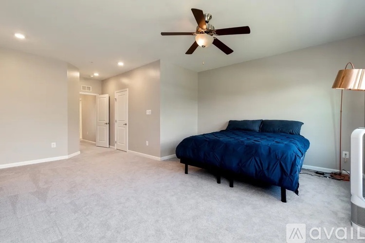 A bedroom with a blue bed and a ceiling fan.