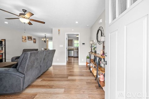 A living room with a grey couch and a fan on the ceiling.