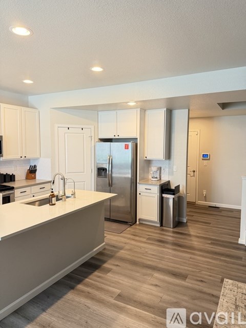 A kitchen with a refrigerator, sink, and cabinets.