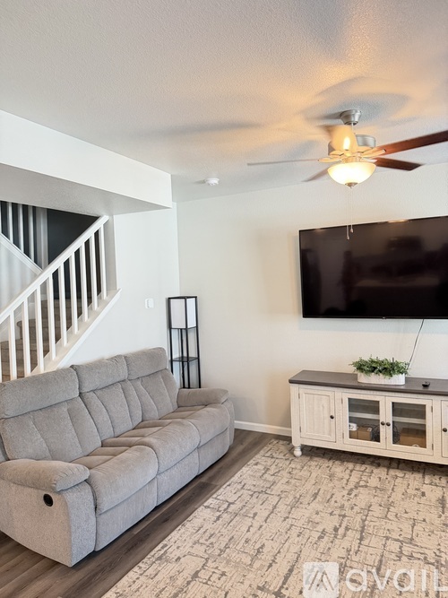A living room with a grey sofa and a television mounted on the wall.