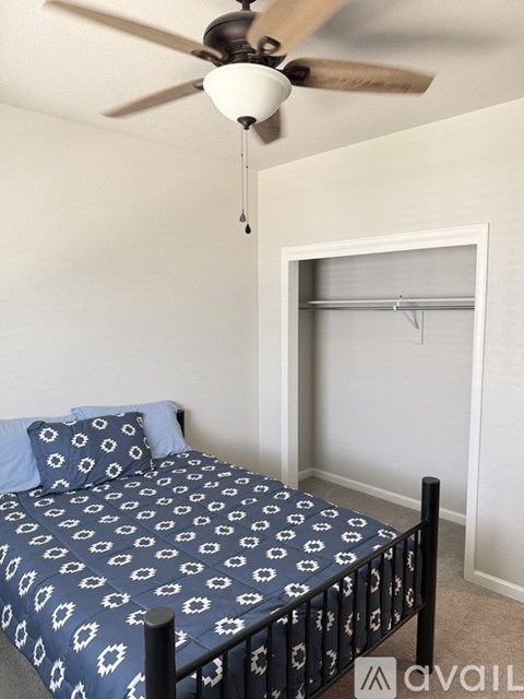 A bedroom with a bed and a ceiling fan.