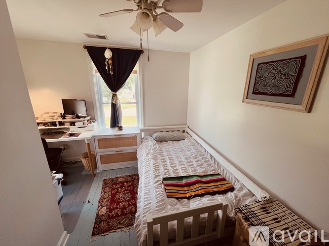 A bedroom with a bed, desk, and window.