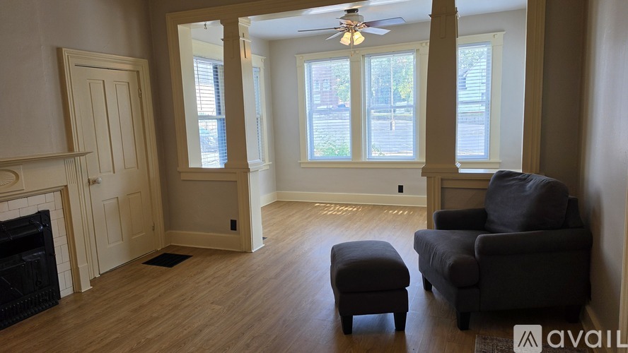 A living room with a fireplace, a chair, and a small ottoman.