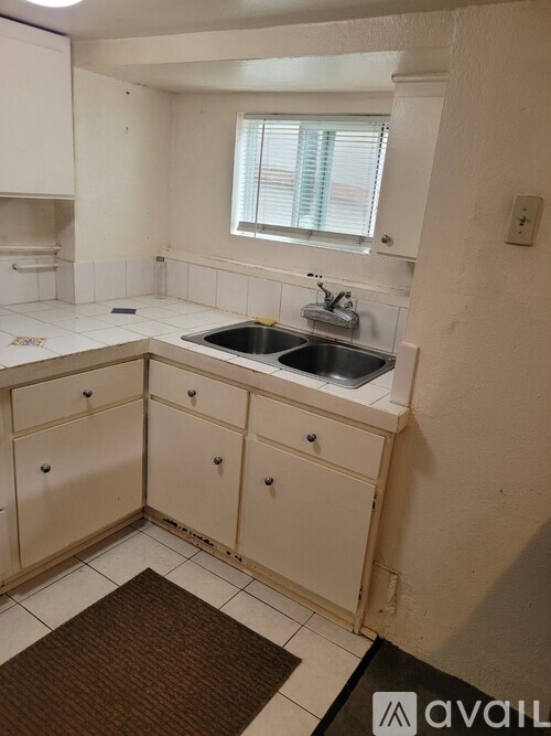A kitchen with white cabinets and a brown rug on the floor.