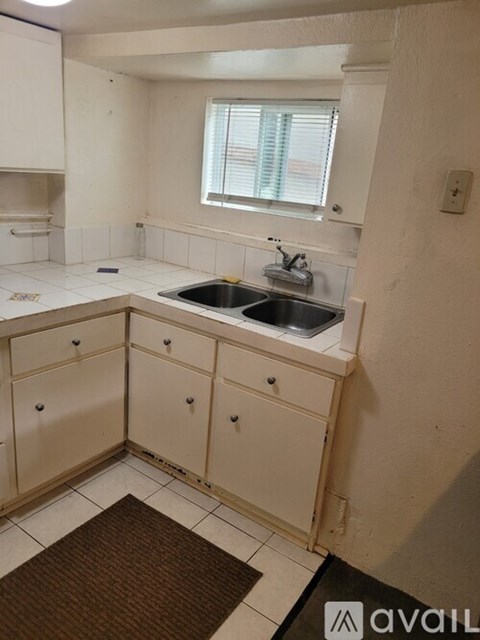 A kitchen with white cabinets and a brown rug on the floor.