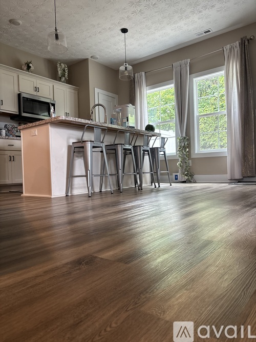 A kitchen with wooden floors and a dining area with chairs.
