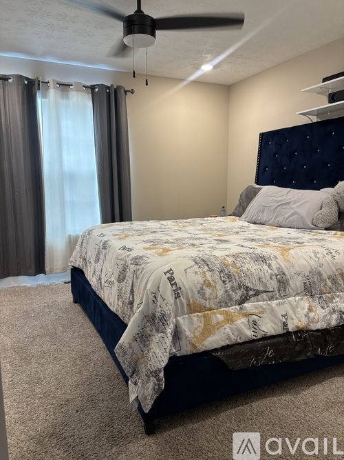 A bedroom with a bed, carpet, and a ceiling fan.