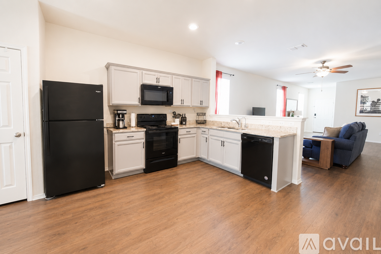 A kitchen with black appliances and wooden floors.