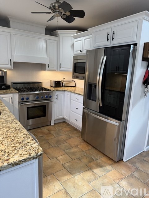 A kitchen with white cabinets and a tile floor.