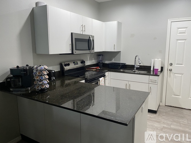 A kitchen with a black countertop and white cabinets.