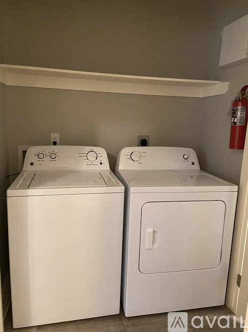 Two white front loading washing machines in a small laundry room.