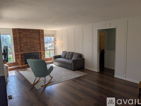 A living room with a rocking chair and a grey couch.