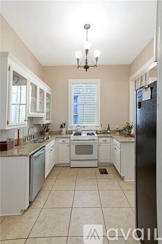 A kitchen with white cabinets and a black refrigerator.