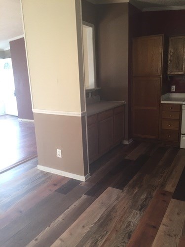A kitchen with a wooden floor and brown cabinets.