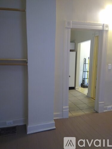 A hallway with a white door and a white wall.